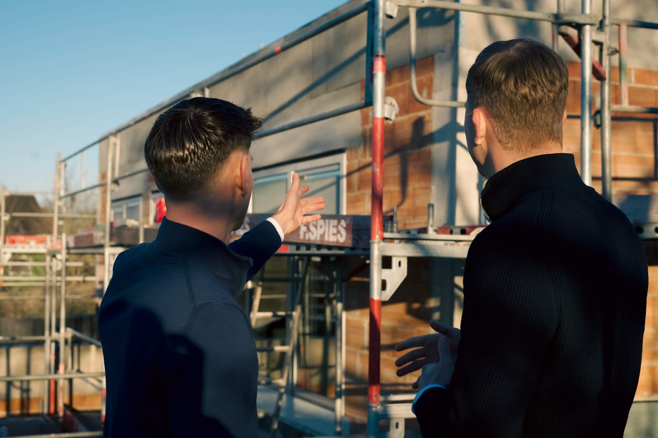 Makler, 2 Junge Männer auf der Baustelle , Schauen den Haus und zeigen darüber