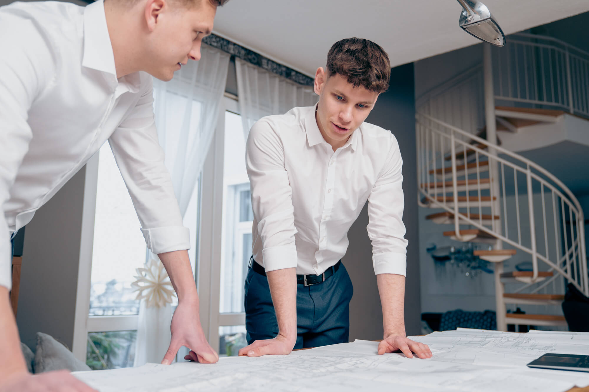 Zwei junge Männer : Jakob Dietl und Nicolas Pfarr beugen sich über ausgebreitete Baupläne und besprechen Details in einem hellen Büro