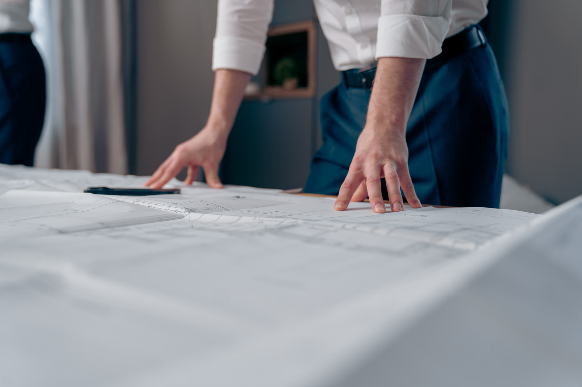 Baupläne auf dem Tisch , und 2 Personen in Hintergrund man kann das Gesicht nicht sehen